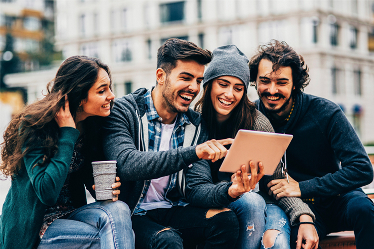 grupo de jóvenes millennials sonrientes consultando una tableta