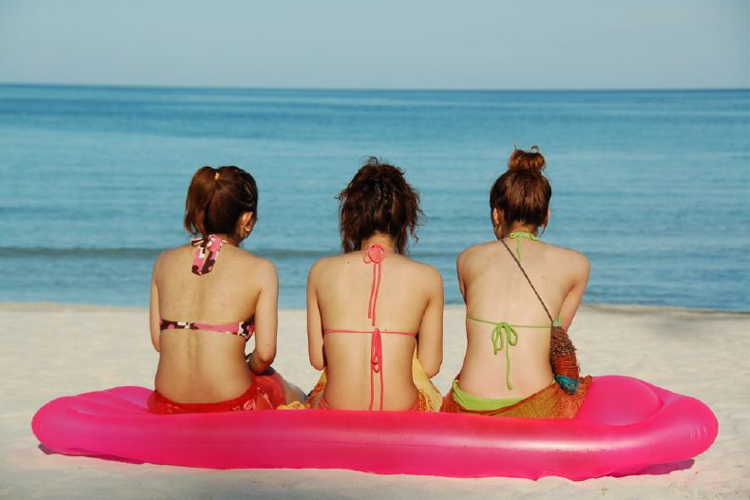  imagen trasera de tres mujeres en bikini contemplando el mar desde la playa