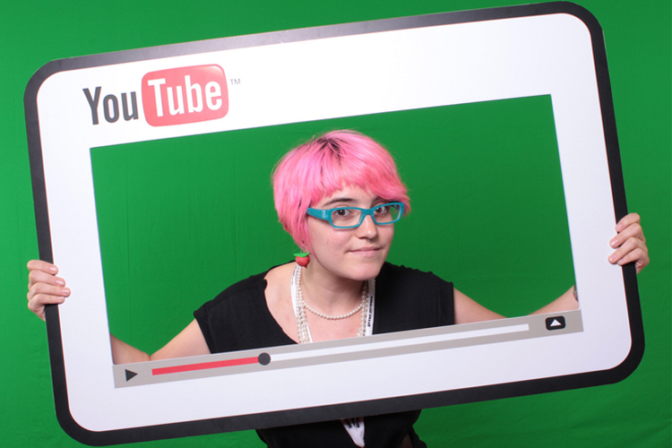 mujer sosteniendo un marco de cartón pluma que simula una pantalla de YouTube