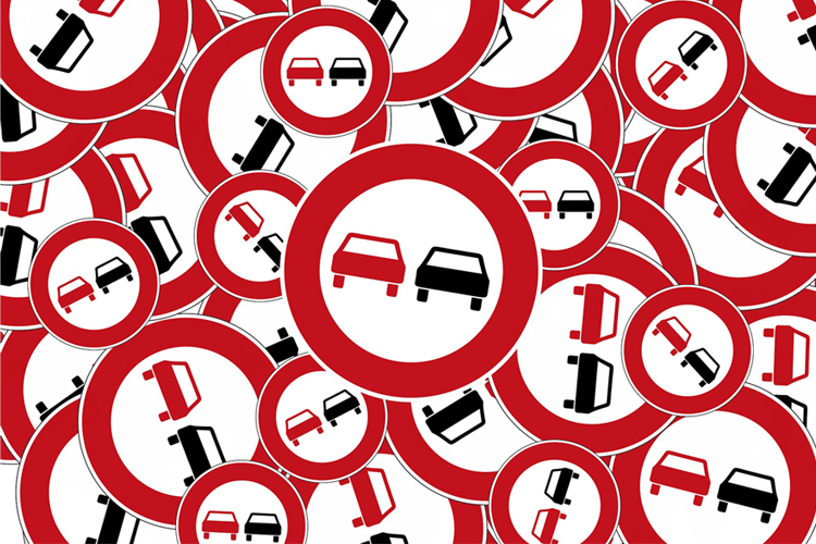 Señales de tráfico de prohibición de adelantar a otros vehículos amontonadas.