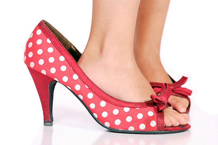 Detalle de unos pies de niña calzados en zapatos de tacón de adulta.
