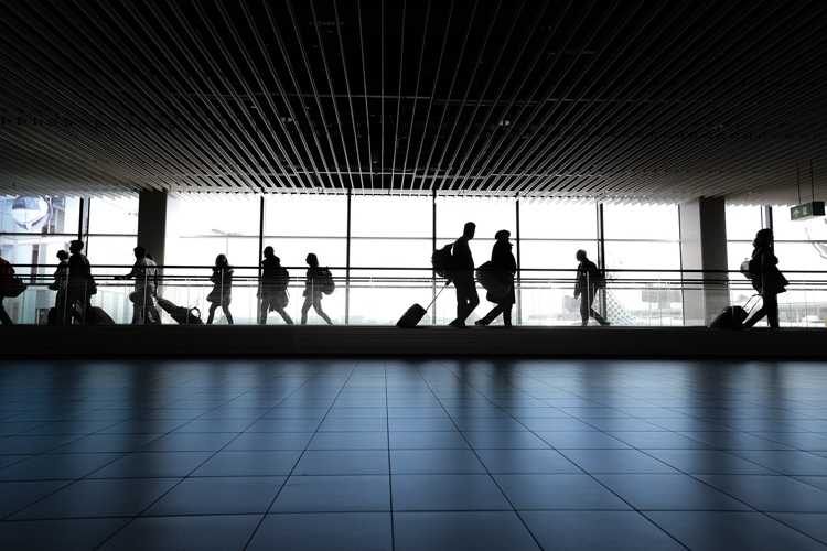 Fotografía de personas con maletas andando por el interior de un aeropuerto.