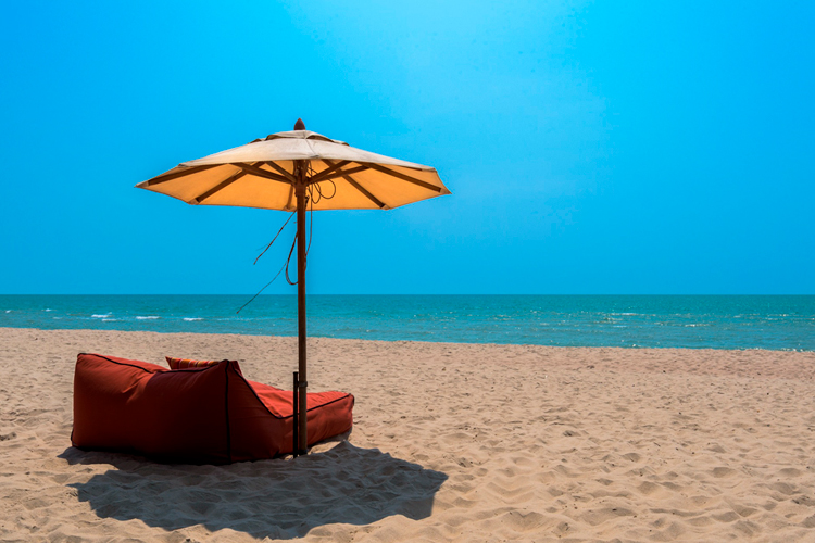 [fotografía] Playa soleada con una tumbona y sombrilla en primer plano