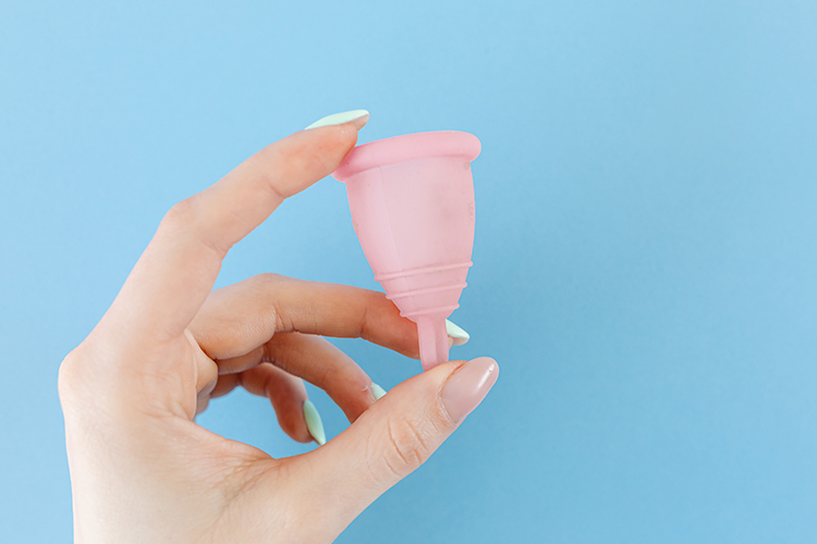 [fotografía] mano femenina sosteniendo una copa menstrual de color rosa