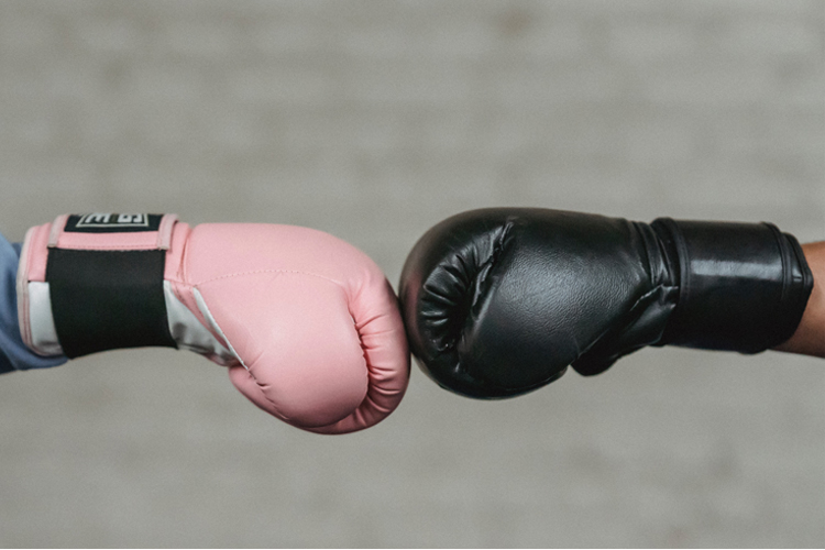 [fotografía] Dos guantes de boxeo (uno rosa y uno negro) tocándose de frente