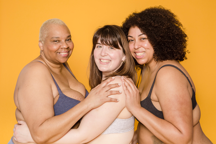 [fotografía] Tres mujeres sonrientes en ropa interior que encajan en lo descrito con el adjetivo 'curvy'