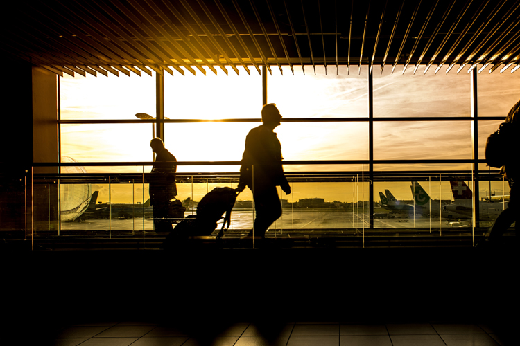 [fotografía] silueta de un pasajero arrastrando su equipaje por la zona de tránsito de un aeropuerto